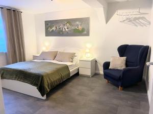 a bedroom with a bed and a blue chair at Casa Bella in Guxhagen