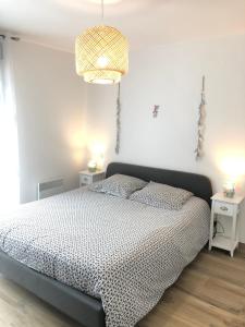 een slaapkamer met een bed en een kroonluchter bij Maison proximité Golf et plage de Bréville sur Mer in Bréville-sur-Mer