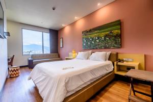 Un dormitorio con una gran cama blanca y una ventana en Diez Hotel Categoría Colombia, en Medellín