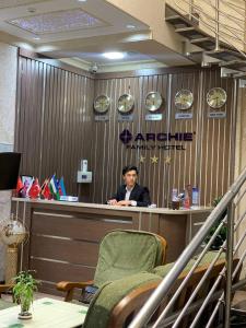 Un uomo seduto al bancone in un ufficio di Archie Family Hotel a Tashkent