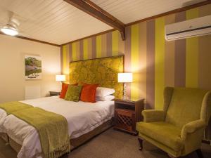 Knysna Log-Inn Hotel في كنيسنا: غرفة نوم بسرير وكرسي
