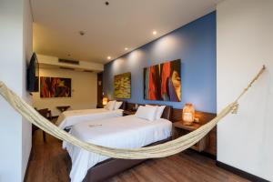 two beds in a room with a hammock at Diez Hotel Categoría Colombia in Medellín