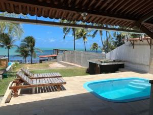 une terrasse avec un bain à remous, des bancs et l'océan dans l'établissement Casa Pé na Areia, à Pirangi do Norte