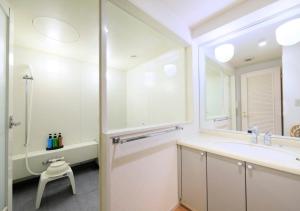 a bathroom with a sink and a tub and a mirror at Kamogawa Grand Tower - Vacation STAY 53387v in Kamogawa