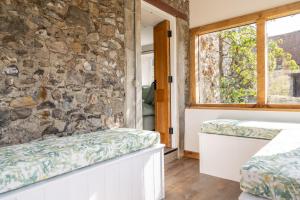 a room with two beds and a stone wall at Charming Family Farmhouse near Lyme Regis in Axminster