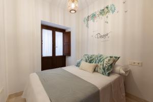 una camera da letto bianca con un letto con cuscini blu di APARTAMENTOS NURIA 19 a Granada