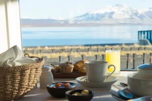 a table with cups and bowls of food and a view of the ocean at Remota in Puerto Natales