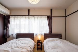 two beds in a bedroom with a window and a lamp at Sennichi House - Vacation STAY 20290v in Kanazawa