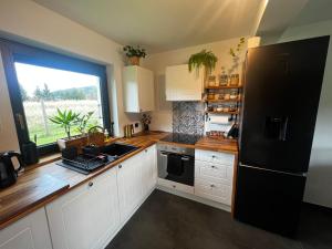 eine Küche mit weißen Schränken und einem schwarzen Kühlschrank in der Unterkunft PETE HOUSE in Ustrzyki Dolne
