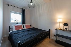 a bedroom with a black bed and a window at Apartamenty Sosnowa - w spokojnej okolicy - Dream Apart in Ustroń