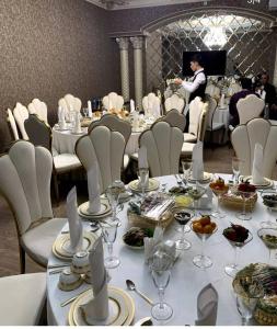 Archie Family Hotel في طشقند: غرفة طعام مع طاولات وكراسي بيضاء ونادل