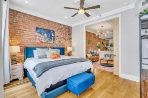 um quarto com paredes de tijolo, uma cama e um banco azul em The Jasmine Nola em Nova Orleans
