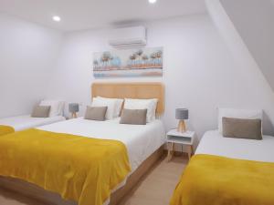Duas camas com lençóis amarelos num quarto branco em Aveiro Ria House E em Aveiro