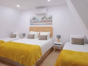 two beds with yellow sheets in a white room at Aveiro Ria House E in Aveiro
