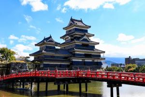 un grand bâtiment avec un pont rouge sur une rivière dans l'établissement Hotel Montagne Matsumoto - Vacation STAY 73659v, à Matsumoto