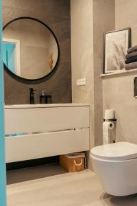 a bathroom with a white toilet and a mirror at Rest In Sanok Apartment in Sanok