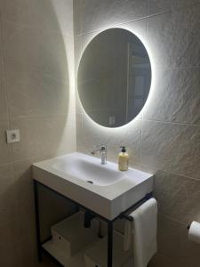 łazienka z umywalką i lustrem na ścianie w obiekcie Apartamento Ayuntamiento Los Candiles w mieście Oviedo