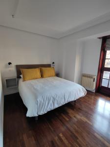 1 cama blanca con 2 almohadas amarillas en un dormitorio en Apartamento Ayuntamiento Los Candiles, en Oviedo