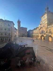 grupa ludzi siedzących pod parasolami na placu w obiekcie Apartamento Ayuntamiento Los Candiles w mieście Oviedo