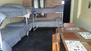 a room with three bunk beds and a table at Hostel el Tata in Potrero de los Funes