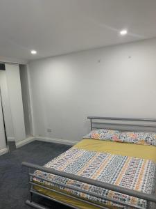 ein Schlafzimmer mit einem Bett und einer weißen Wand in der Unterkunft Sam’s House in Purley