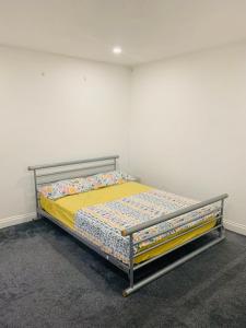 Bett in einem Zimmer mit einer weißen Wand in der Unterkunft Sam’s House in Purley