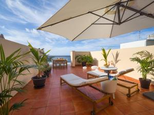 a patio with an umbrella and a table and chairs at Giraud II - Beachfront - Pool - 46 m2 Terrace in Santa Maria de Guia de Gran Canaria