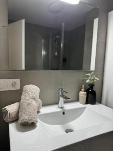 un bagno bianco con lavabo, specchio e asciugamani di Liège Luxe & Jacuzzi sous les étoiles a Saint-Nicolas