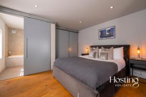 a bedroom with a large bed and a bathroom at Modern Luxury Apartment In The Heart of Henley in Henley on Thames