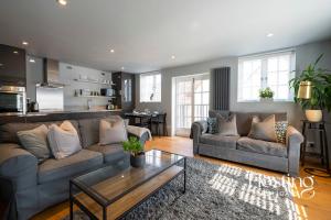 a living room with two couches and a table at Modern Luxury Apartment In The Heart of Henley in Henley on Thames