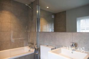 La salle de bains est pourvue d'un lavabo, d'une baignoire et d'une douche. dans l'établissement Modern Luxury Apartment In The Heart of Henley, à Henley-on-Thames