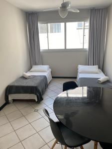 a room with two beds and a table and a window at Innbox - Canasvieiras 2 in Florianópolis