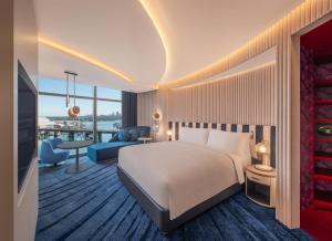 シドニーにあるW Sydneyのベッドとリビングルームが備わるホテルルームです。