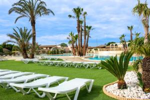 a row of white lounge chairs in front of a pool at Maison à Portiragnes Plage - Résidence les Tamaris - Porte du Soleil - Prix piscine comprise in Portiragnes