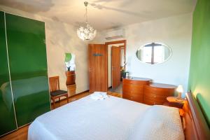 1 dormitorio con cama blanca y pared verde en monica Casa Vacanza en Busto Arsizio
