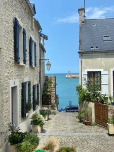 a cobblestone street between two buildings with a view of the ocean at L'Escale Portaise in Port-en-Bessin-Huppain