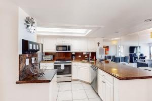 a large kitchen with white cabinets and appliances at Ocean Vista #102 in South Padre Island