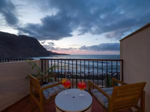 Un balcón con 2 sillas y una mesa con vistas al océano. en Giraud II - Secluded beachfront duplex, en Santa María de Guía de Gran Canaria