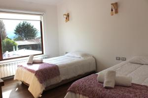 a bedroom with two beds and a large window at Hostal Alamo Patagonico in Puerto Natales