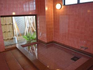 ein rot gefliestes Bad mit einer Badewanne und einem Fenster in der Unterkunft Hotel Akaboshitei - Vacation STAY 49555v in Echizen