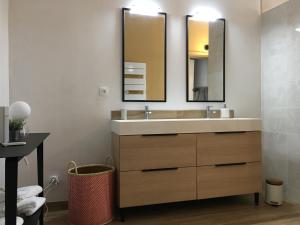 a bathroom with a sink and two mirrors at Appartements Plantagenet - Le 33 in Le Mans