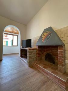 een woonkamer met een stenen open haard en een tv bij Agriturismo Nonno Dante - Casa Moraiolo in Castiglion Fibocchi