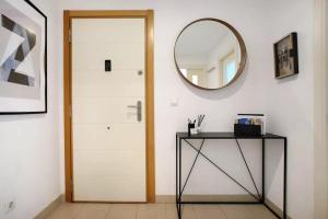 pasillo con puerta y mesa con espejo en MALAGA CAMPUS APARTMENT Piscina y Parking incluido, en Málaga