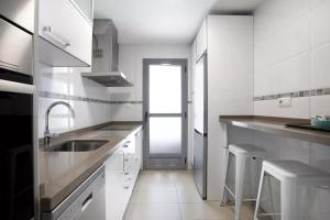 a white kitchen with a sink and a door at MALAGA CAMPUS APARTMENT Piscina y Parking incluido in Málaga