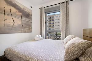 a bedroom with a white bed and a window at MALAGA CAMPUS APARTMENT Piscina y Parking incluido in Málaga