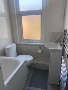 uma casa de banho com um WC, um lavatório e uma janela em Cosy house in Newham em Londres