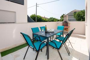 um pátio com uma mesa preta e cadeiras azuis em Apartment Cosic em Vir