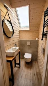 Un baño con lavabo, inodoro y ventana. en Domki Całoroczne nad Morzem Kraina Bałtyku, en Przewłoka