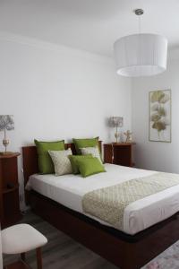 um quarto com uma cama grande e almofadas verdes em ARRUDA LUXURY APARTMENT with AC em Cascais