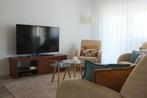 a living room with a tv and two chairs and a table at ARRUDA GARDEN LUXURY APARTMENT with AC in Cascais